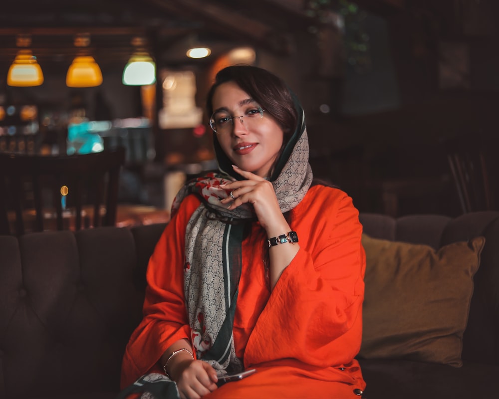 a woman sitting on a couch wearing a scarf