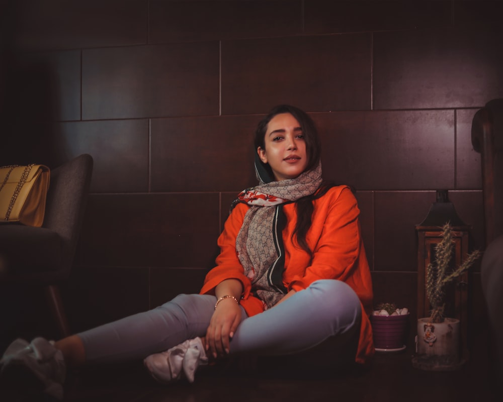 a woman sitting on the floor with a scarf around her neck