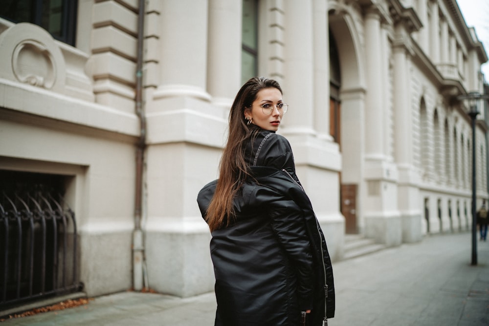 a woman in a black coat is standing on the street