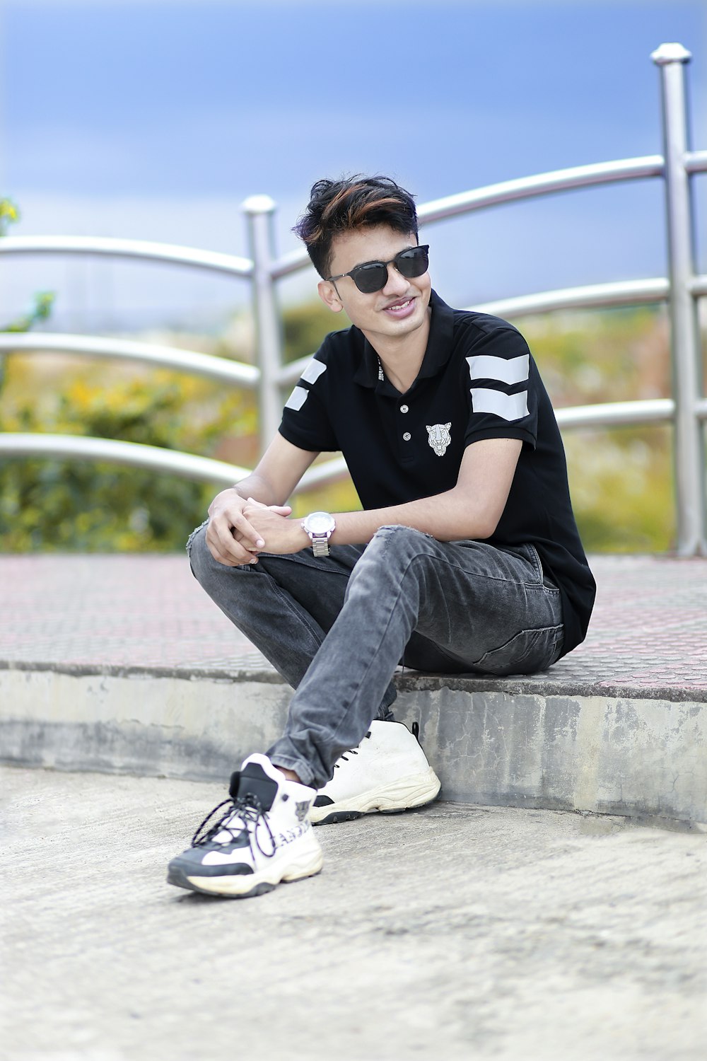 a young man sitting on the steps wearing sunglasses