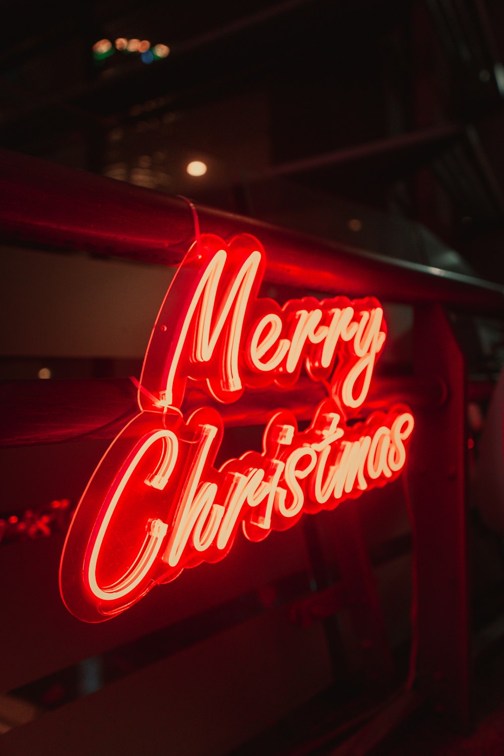 a red merry christmas neon sign hanging from the side of a building