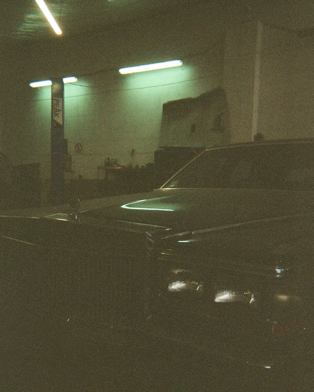 a black car parked in a garage next to another car
