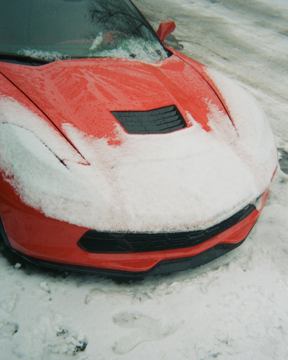 a red sports car is covered in snow