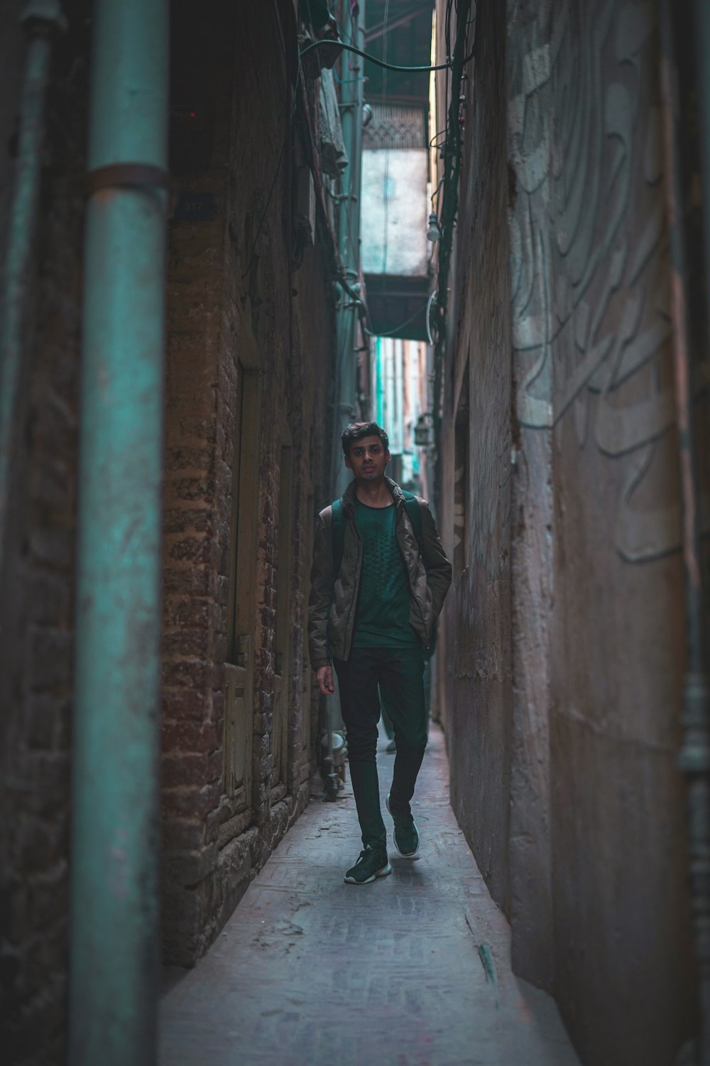 a man walking down a narrow alley way