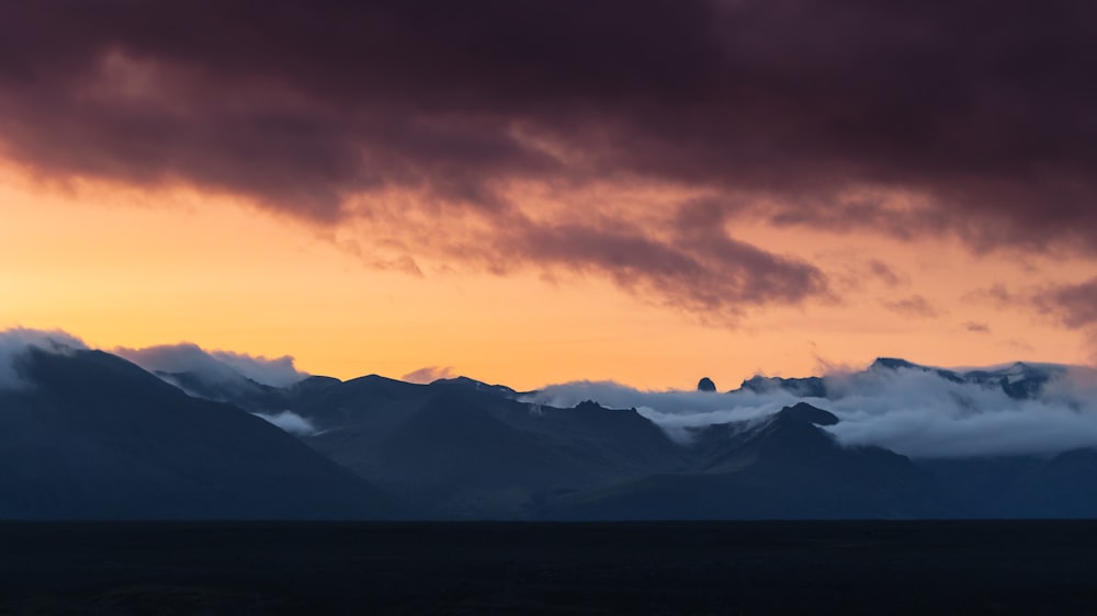 a mountain range with clouds in the sky