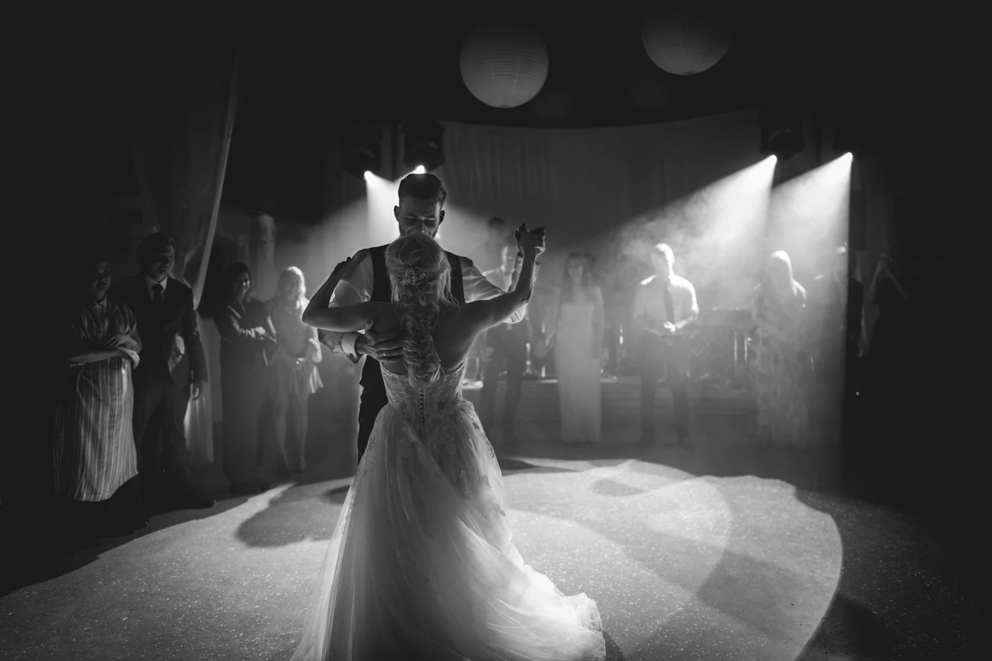 Couple sharing a spotlit first dance surrounded by guests at a wedding reception