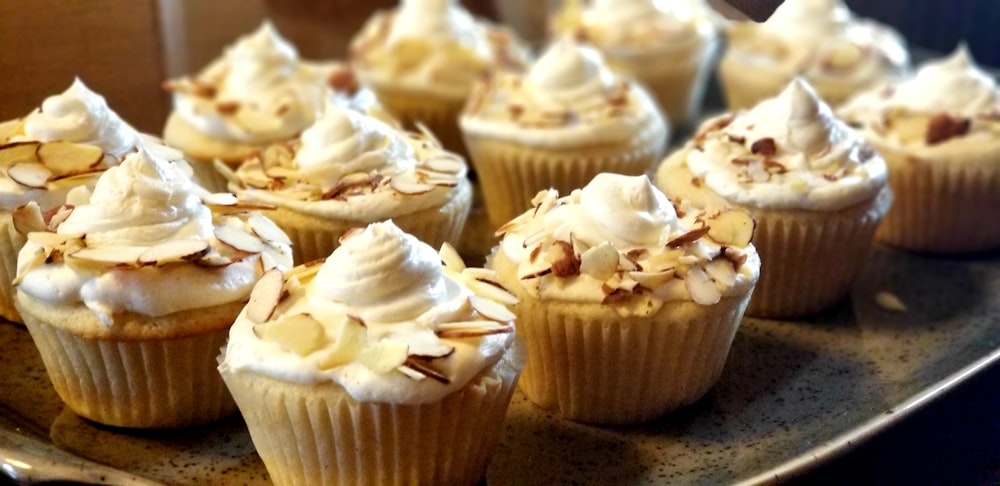 a plate of cupcakes with white frosting and nuts