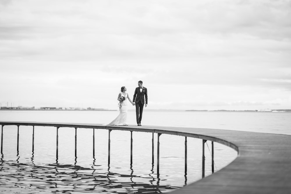 a bride and groom standing on a pier