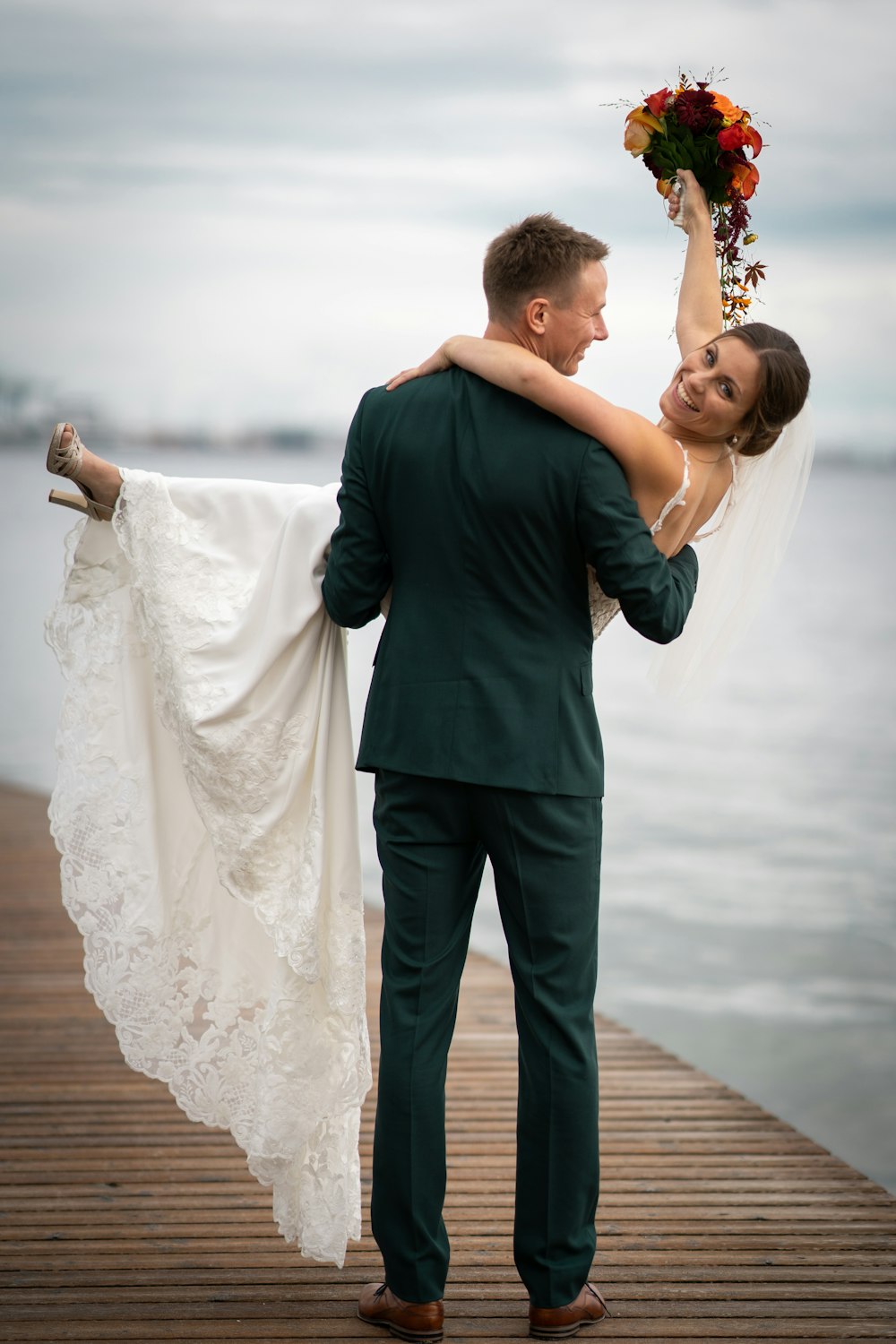 a bride carrying her groom on a dock
