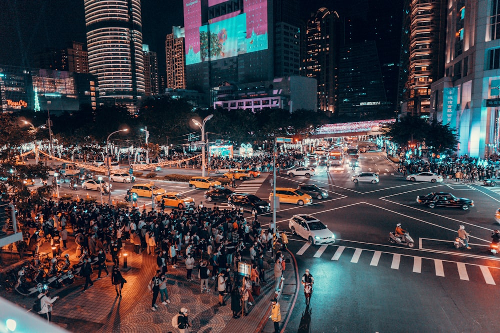 a crowd of people standing on a street at night