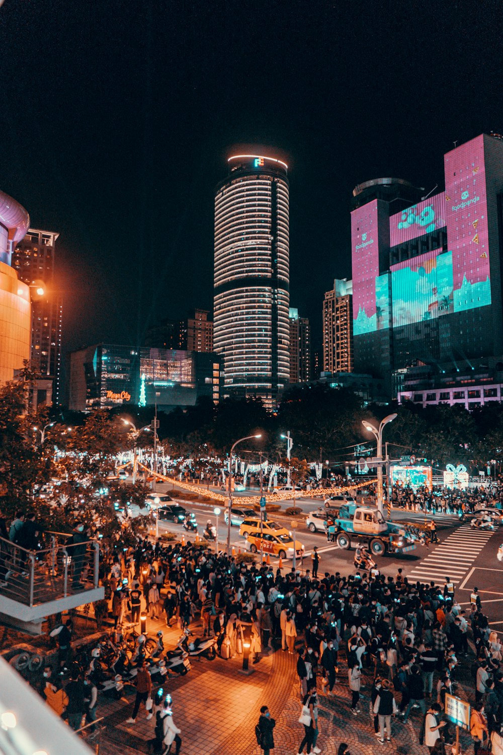 a crowd of people standing on a street next to tall buildings