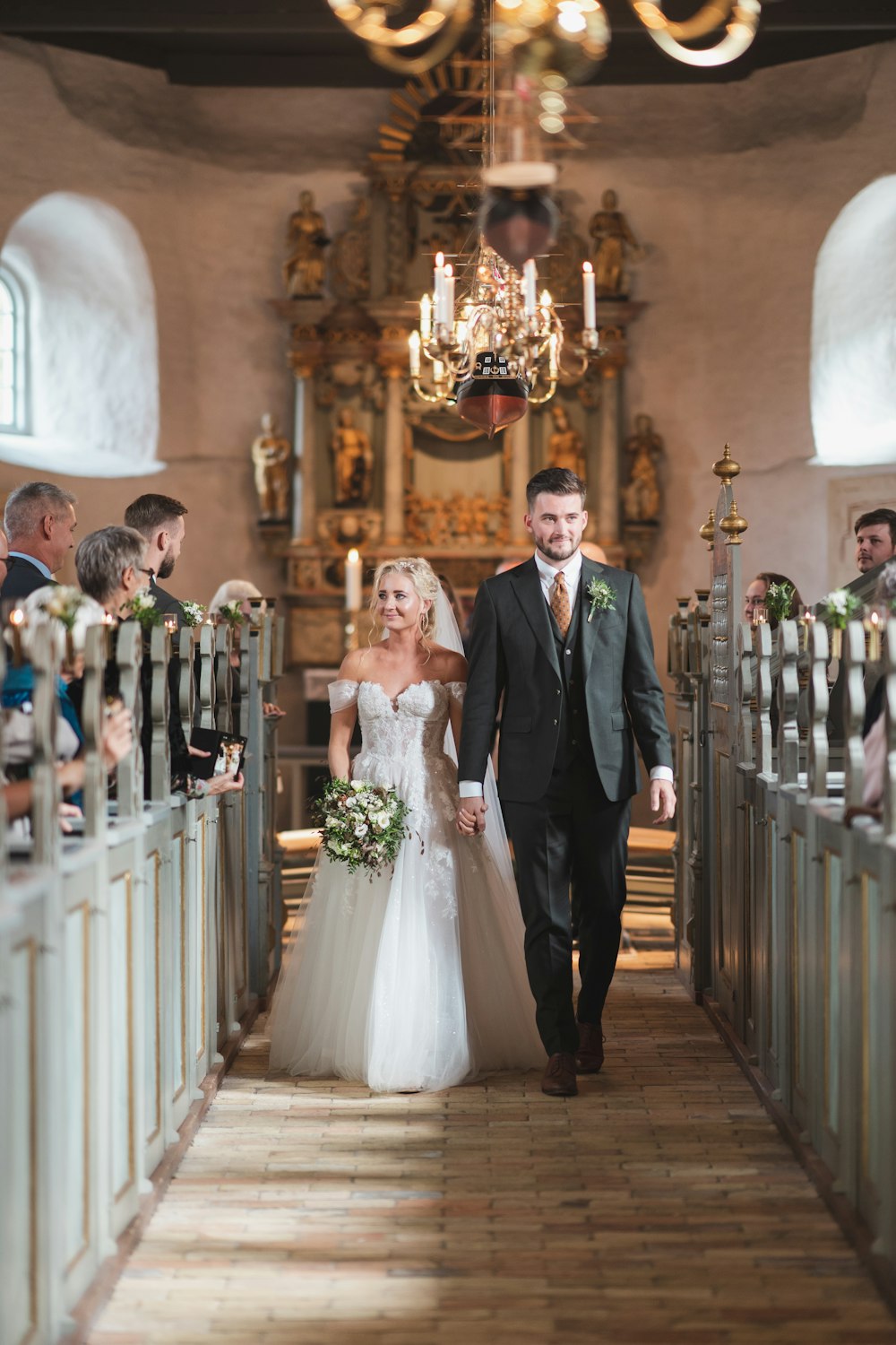 a bride and groom walking down the aisle of a church