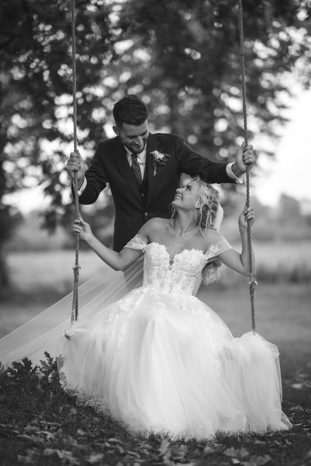 a bride and groom sitting on a swing