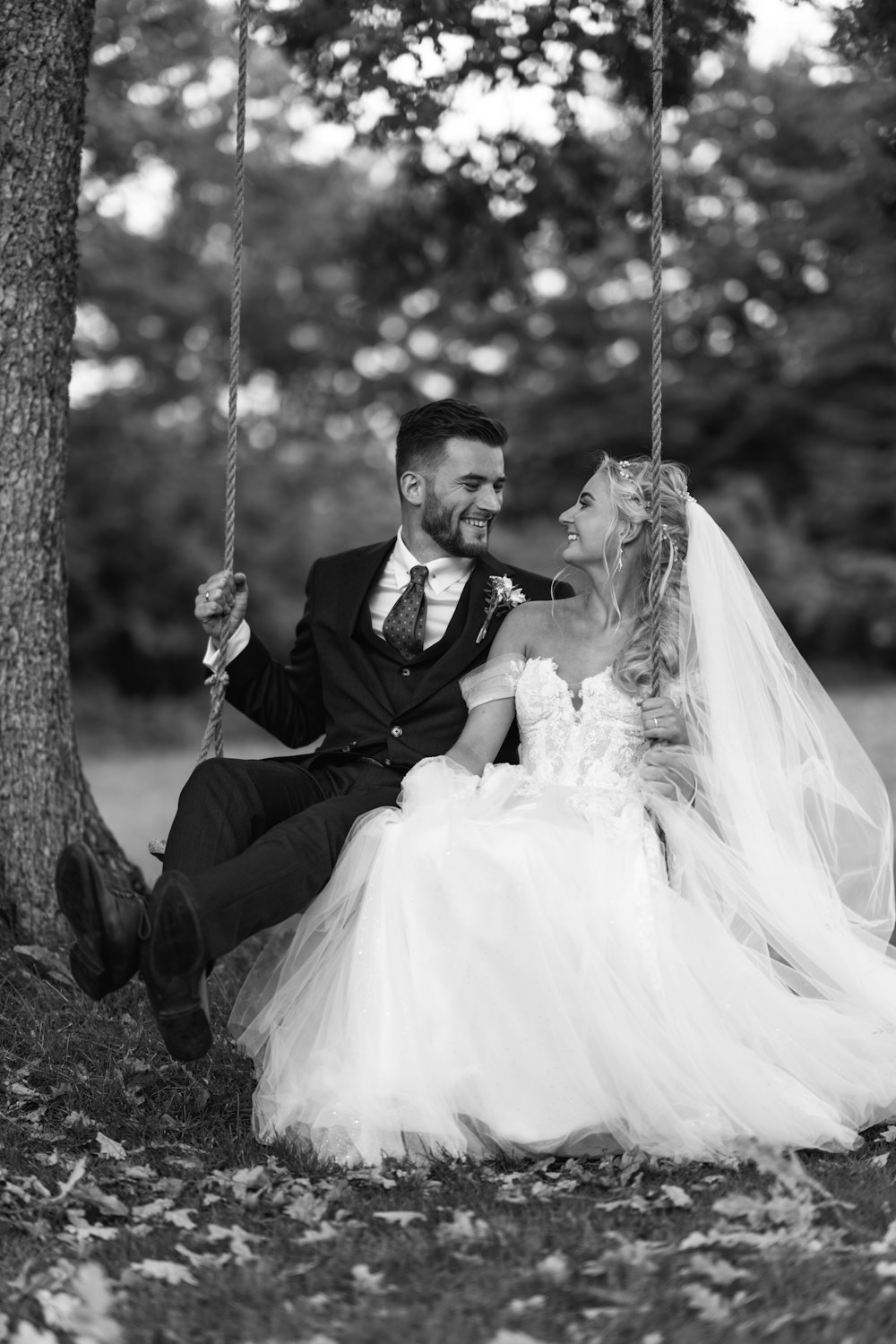 a bride and groom sitting on a swing