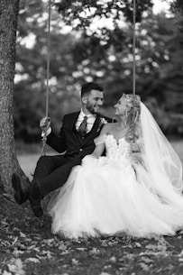 a bride and groom sitting on a swing