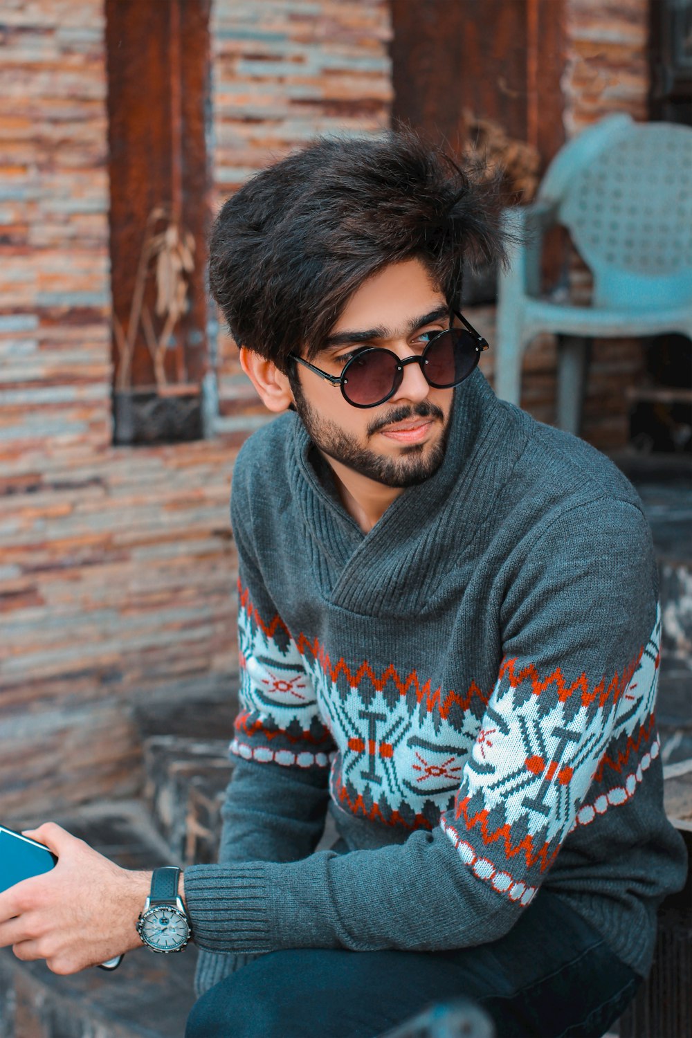 a man sitting on a bench wearing a sweater and sunglasses