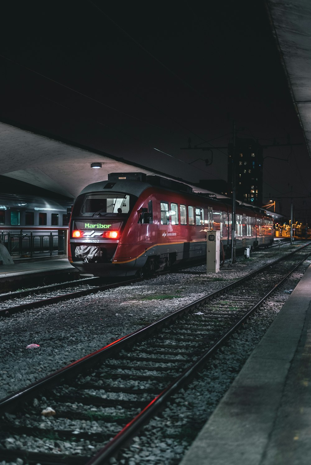 a red train pulling into a train station at night