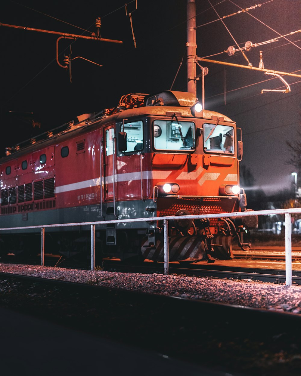 a red train traveling down train tracks at night