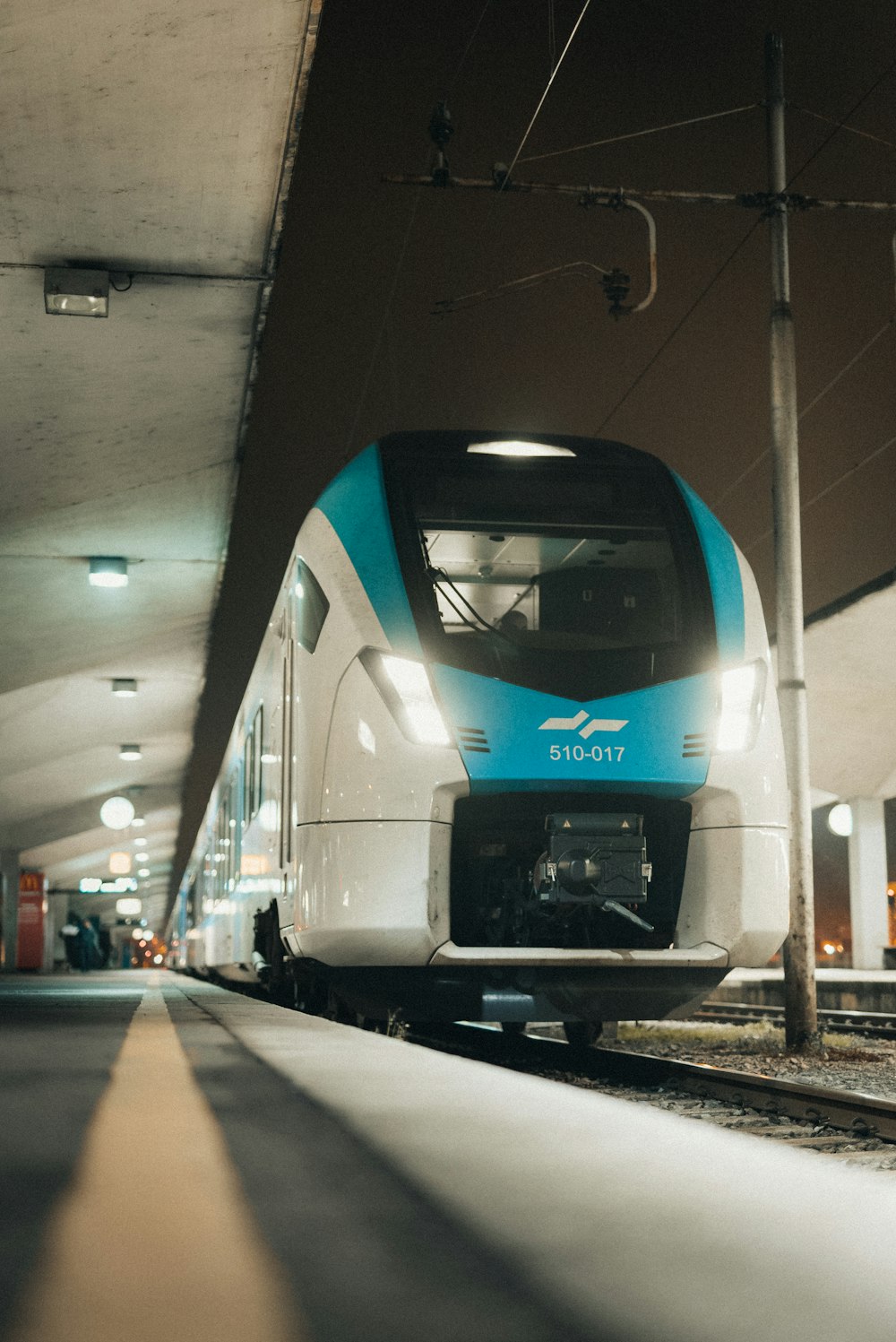 a blue and white train pulling into a train station