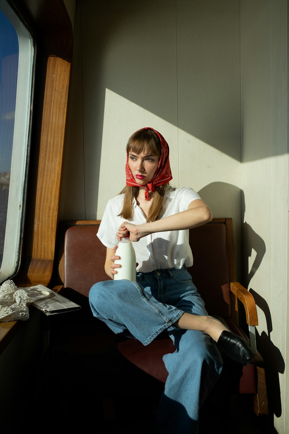 a woman sitting on a chair with a red scarf around her head