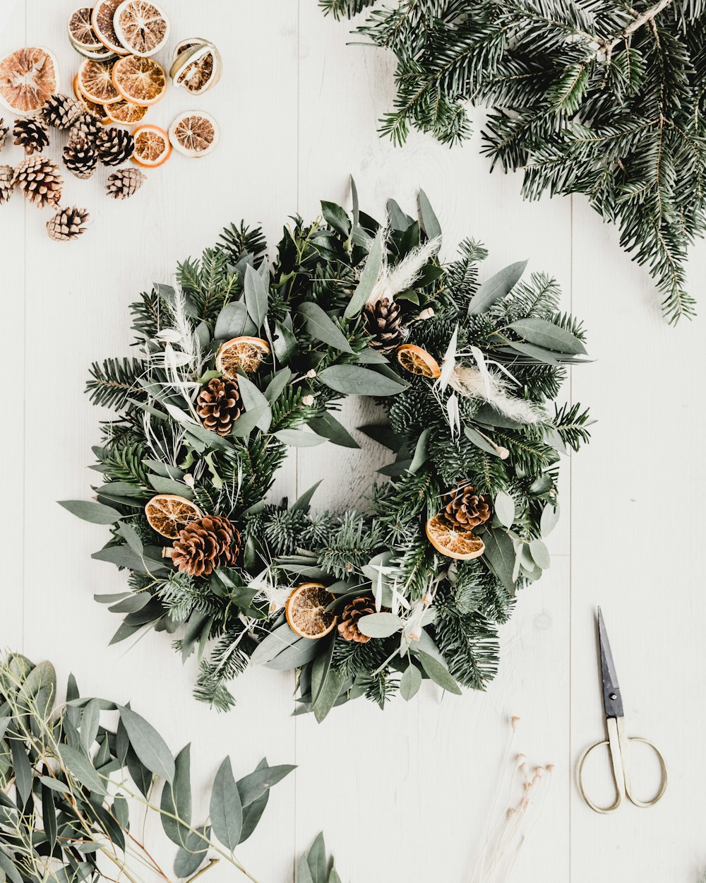 a wreath with pine cones and evergreen leaves