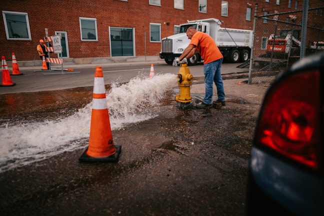a man in an orange shirt is working on a fire hydrant