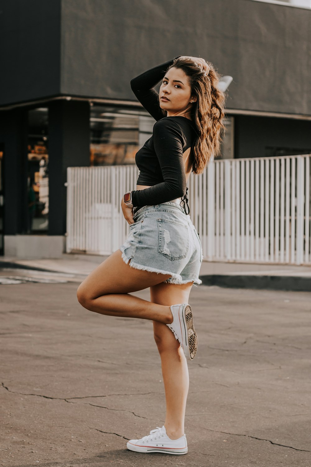 a woman standing in a parking lot with her legs crossed