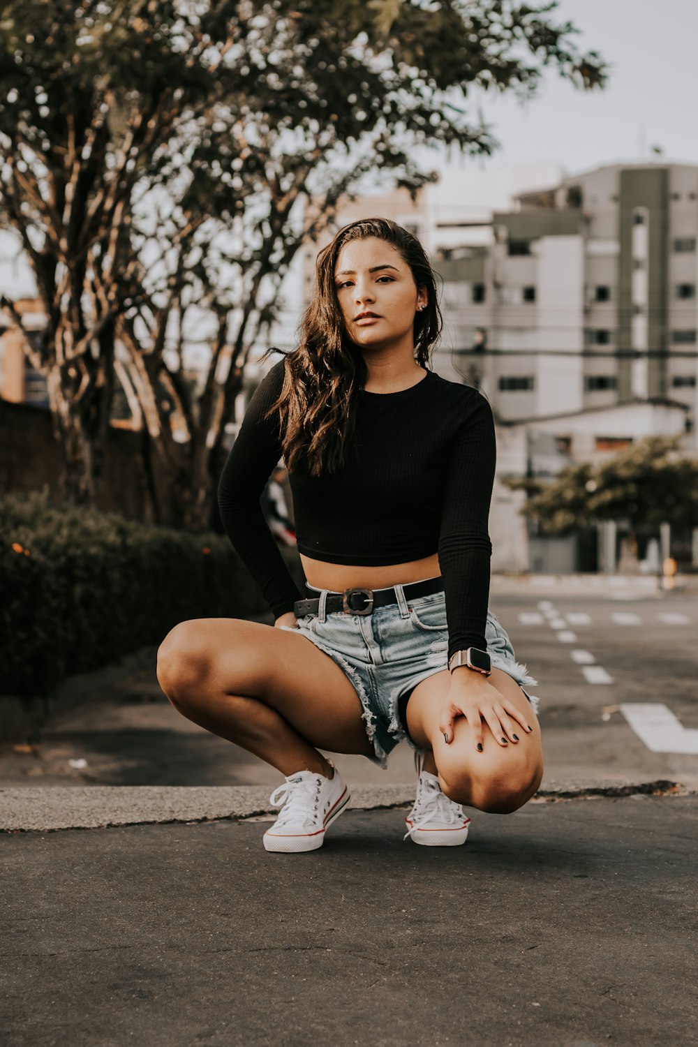 a woman kneeling down in the street with her hands on her hips