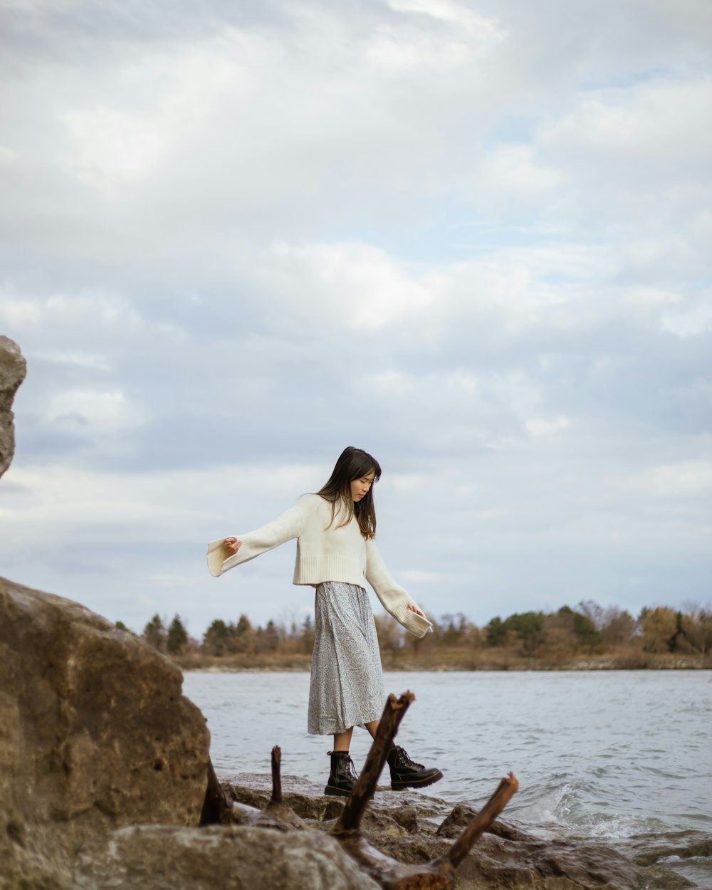 a woman standing on a rock near a body of water