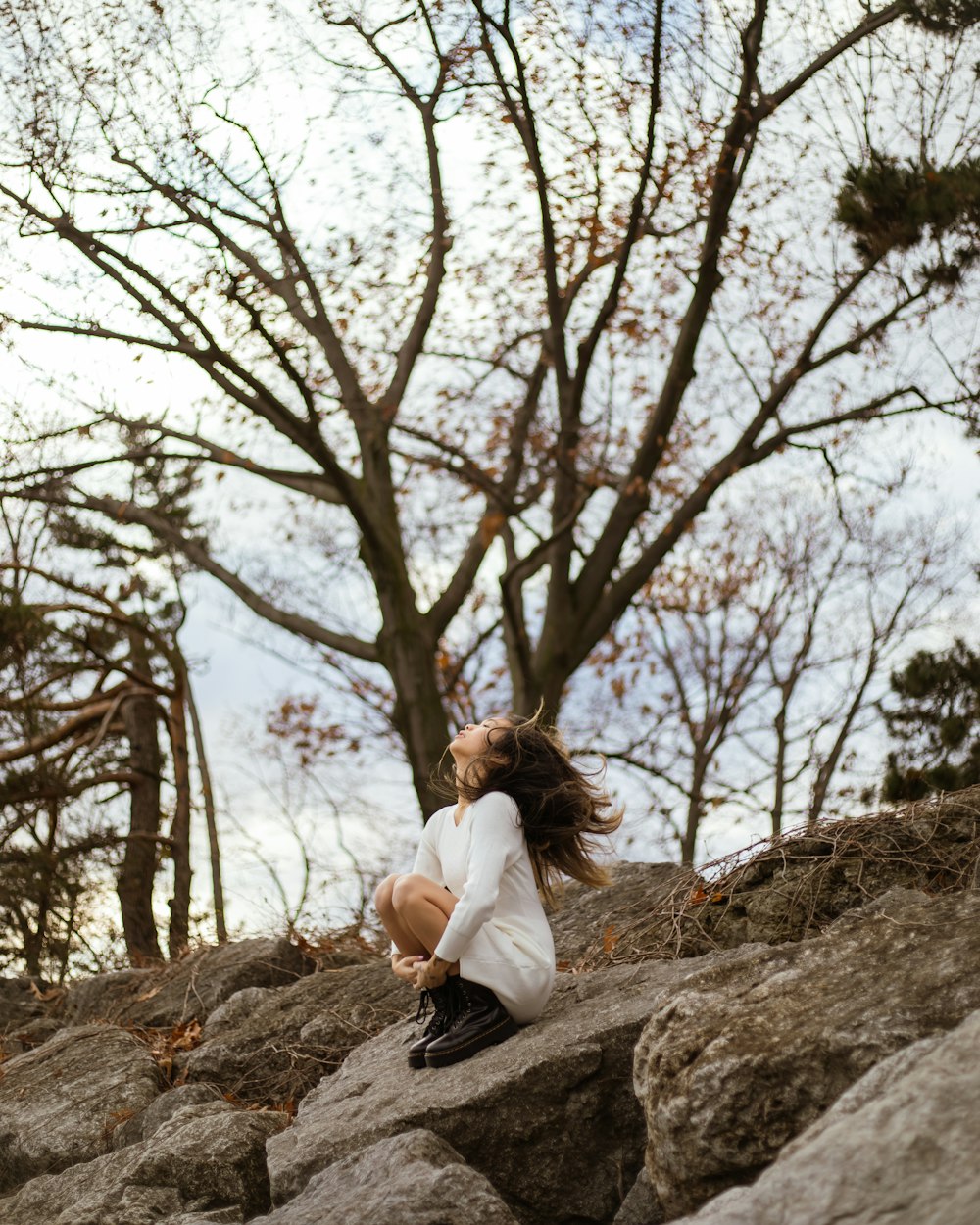 a girl sitting on a rock in the woods