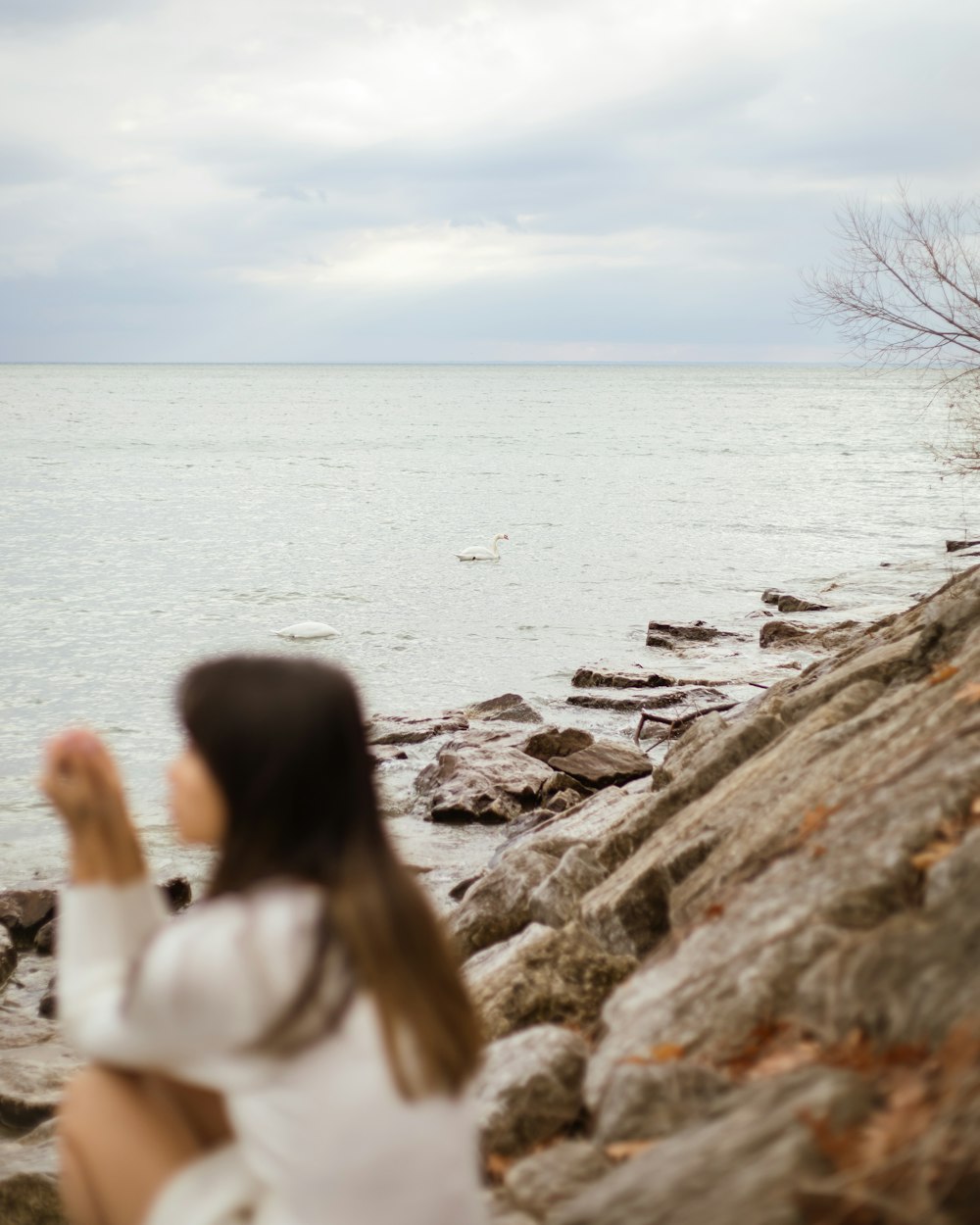 a woman sitting on a rock near the water