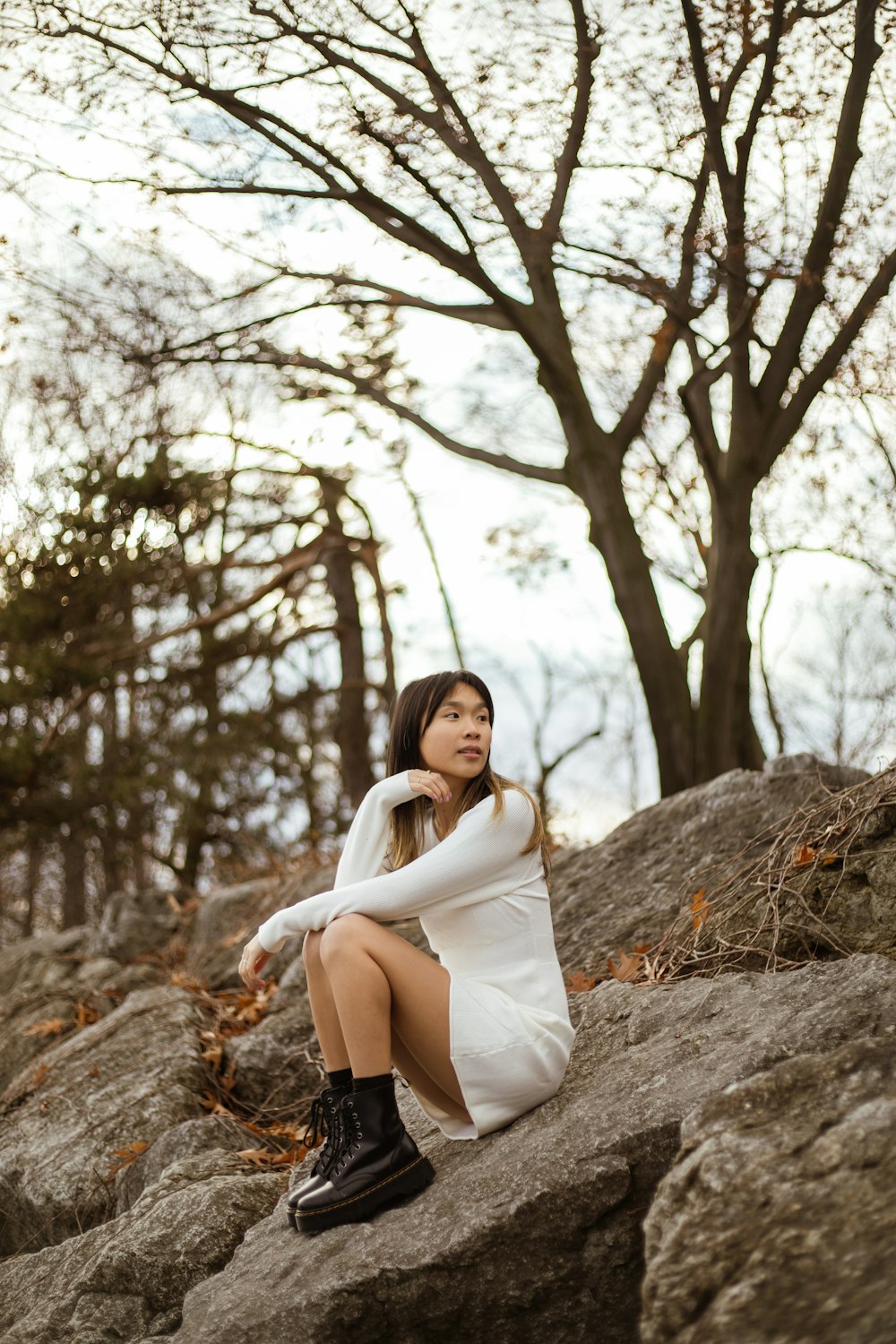 a woman sitting on top of a rock next to a tree