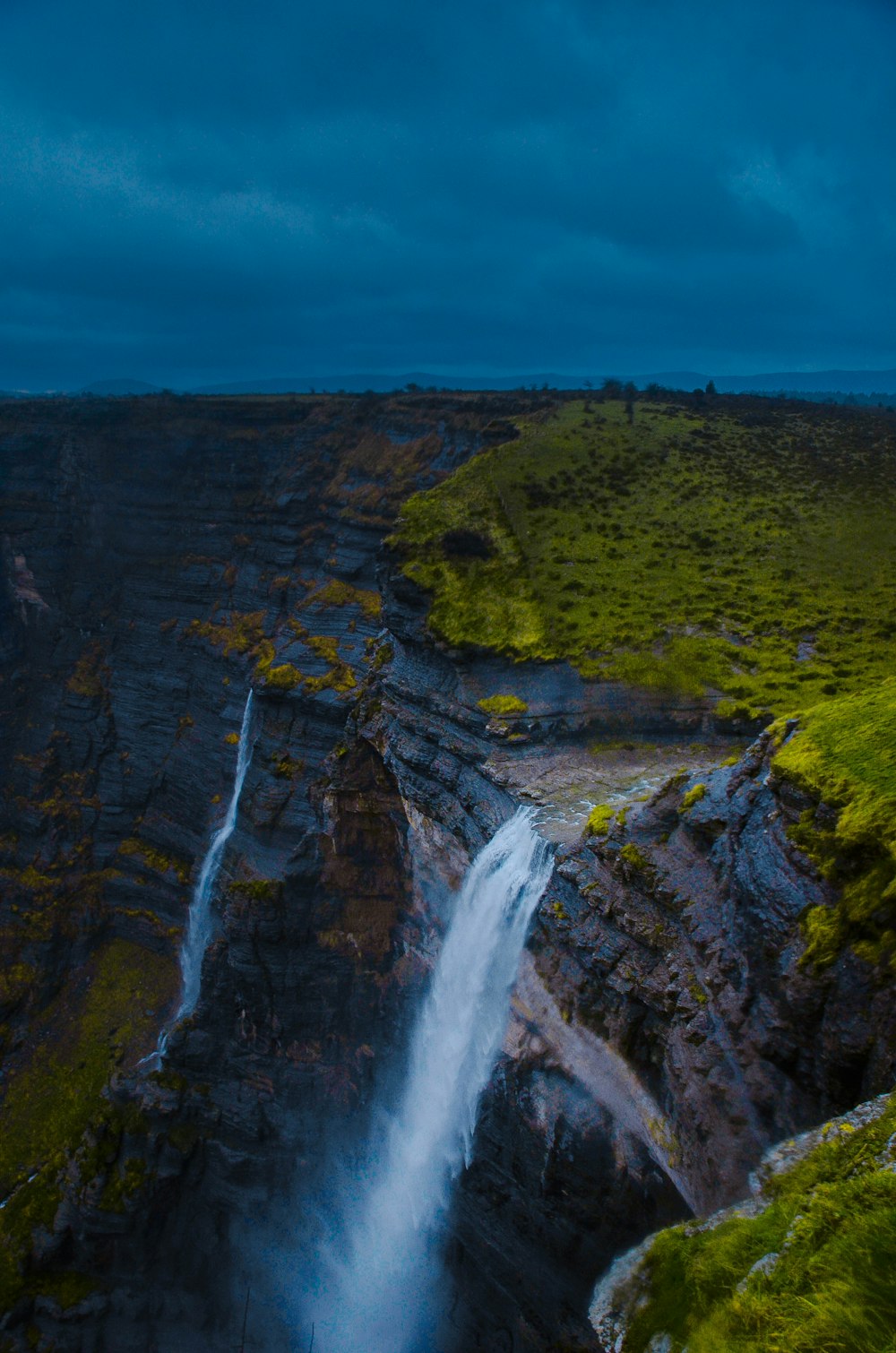 a waterfall in the middle of a green field