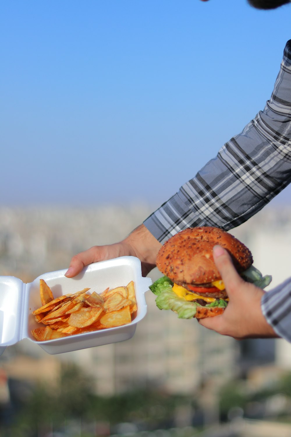 a person holding a container with a hamburger and french fries in it