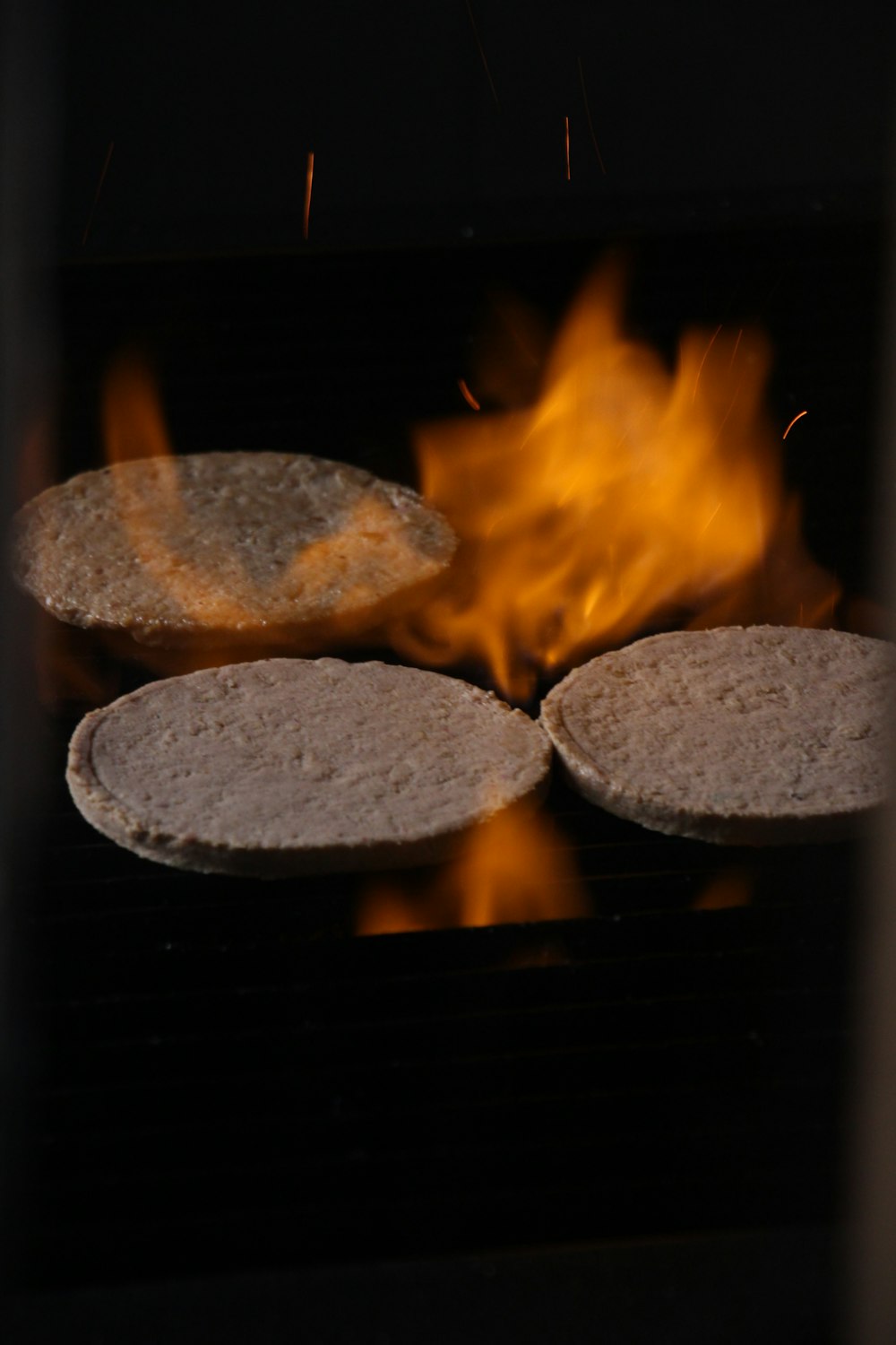 two pita breads cooking on a grill with flames