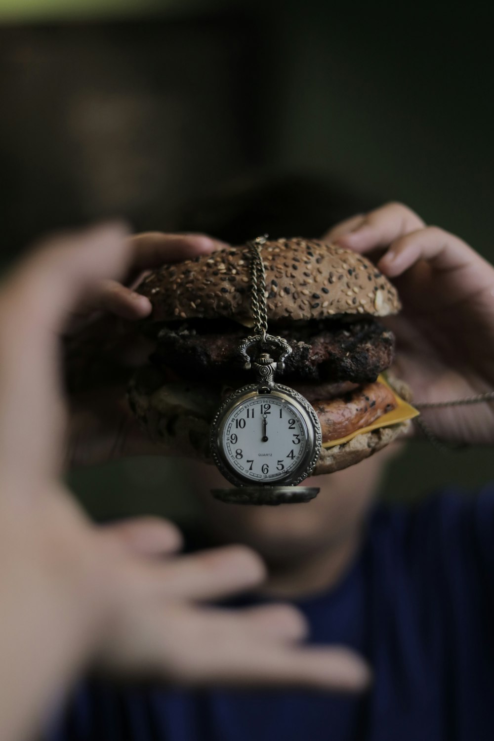 a person holding a clock in front of a hamburger