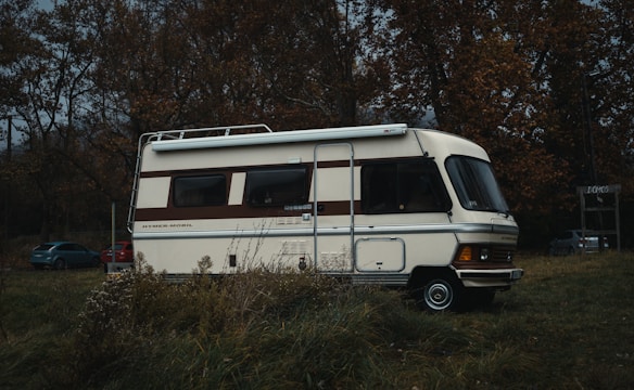 a motor home parked in a field next to a forest