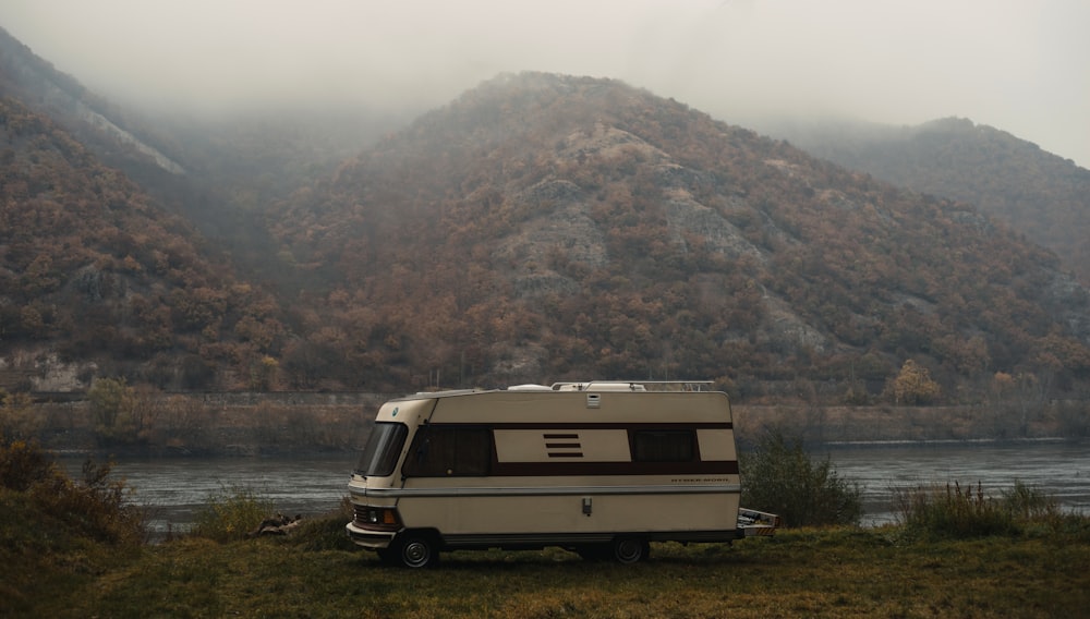 an rv parked in a field next to a body of water