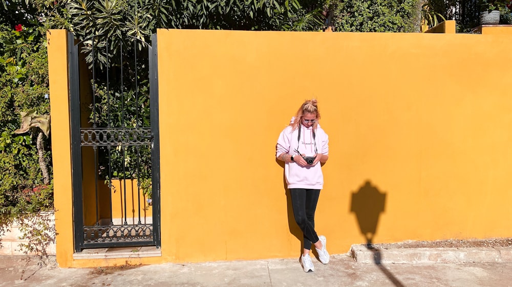 a woman standing in front of a yellow wall