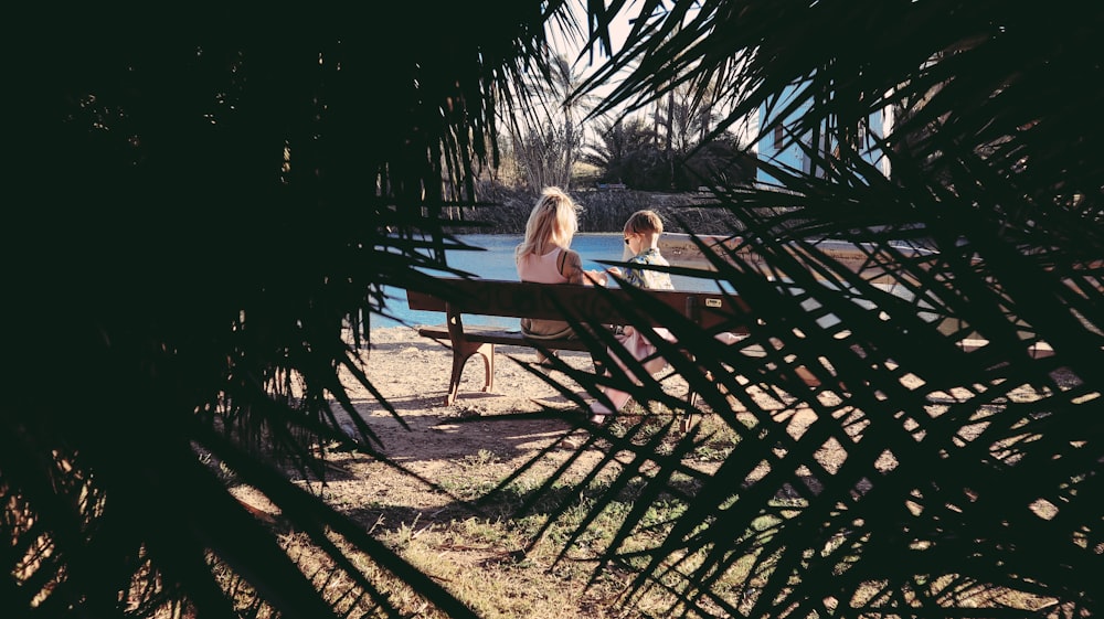 a couple of women sitting on top of a bench