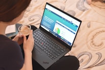 a woman sitting on a bed looking at a laptop