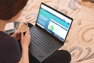 a woman sitting on a bed looking at a laptop