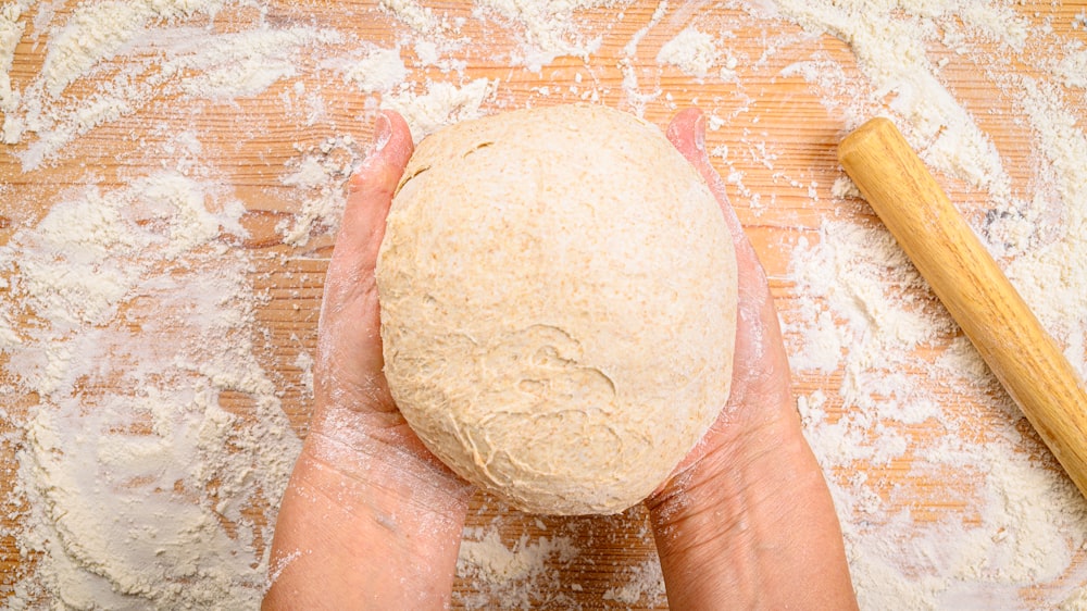 a person holding a ball of bread in their hands