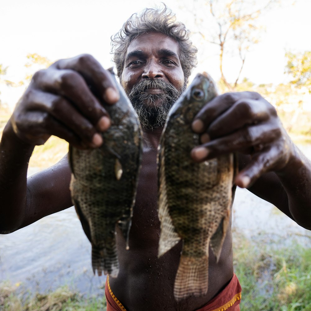 a man holding two fish in his hands