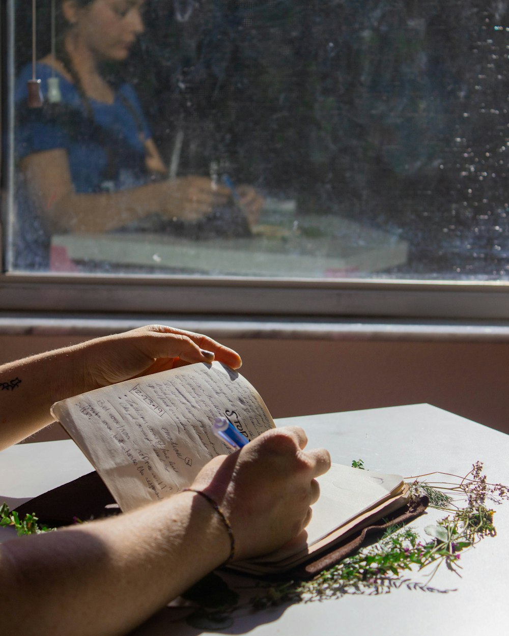 a person sitting at a table writing on a piece of paper