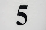 A curb painted with a simple but elegant address number in black on a white background.