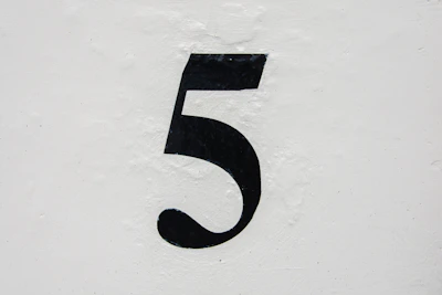 A curb painted with a simple but elegant address number in black on a white background.