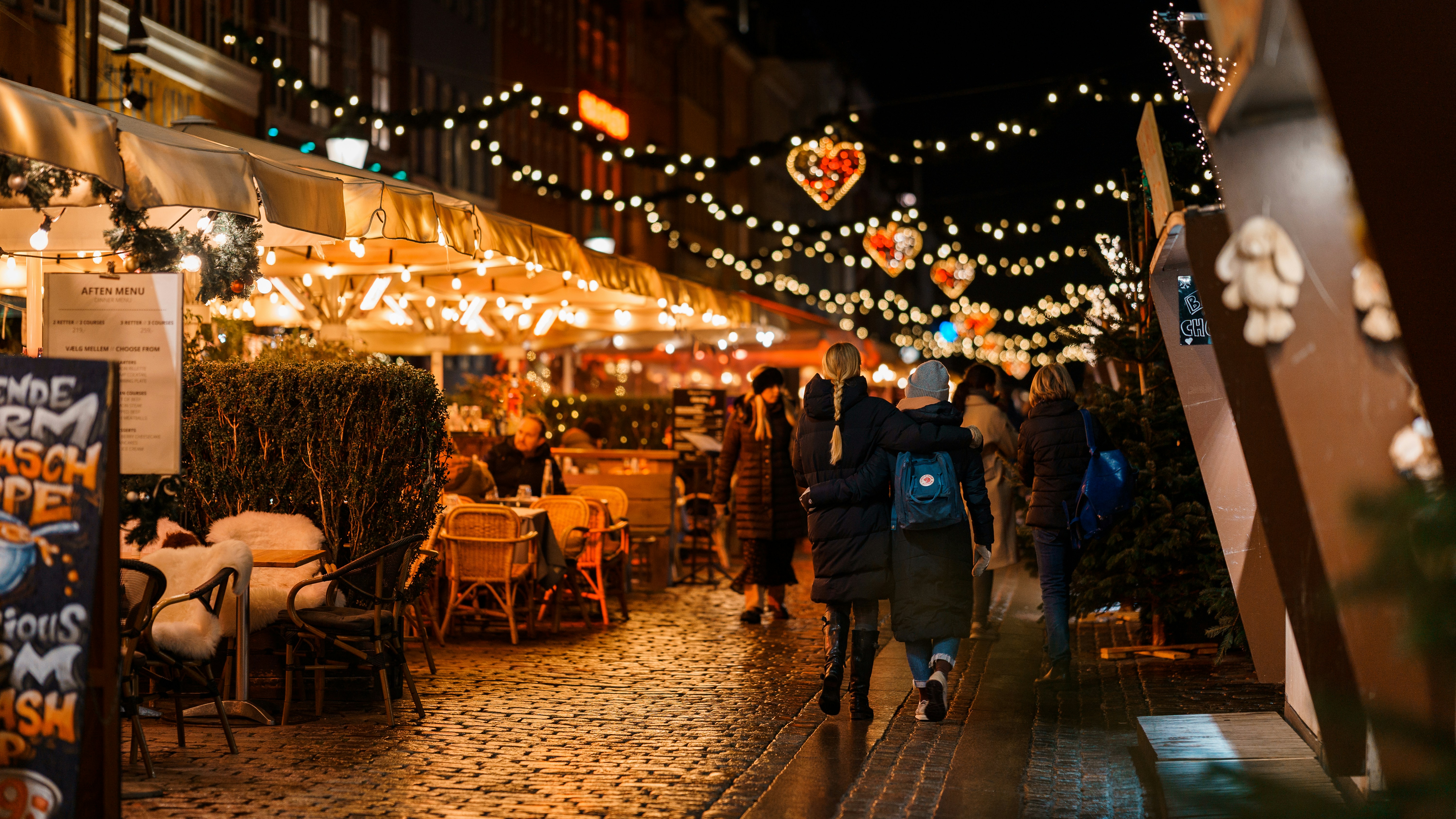 a group of people walking down a street at night