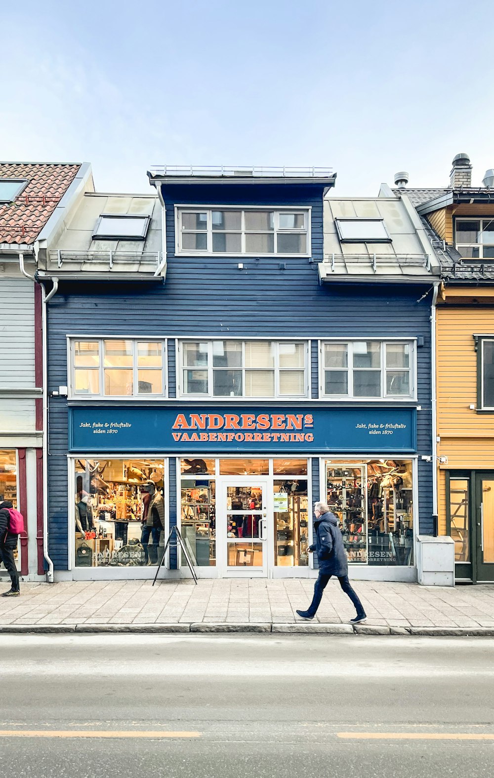 a man walking down the street in front of a store