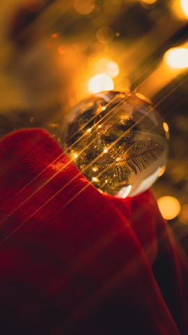 Colorful glass baubles reflecting warm holiday lights on a decorated pine branch.